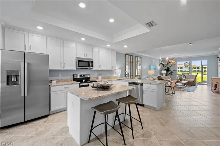 Kitchen with stainless steel appliances, a tray ceiling, ornamental molding, a peninsula, and recessed lighting