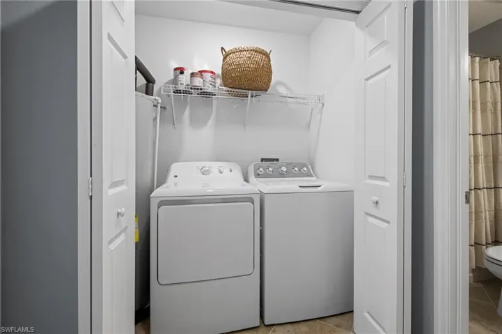 Laundry area with separate washer and dryer and light tile patterned floors