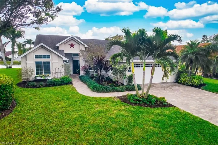 View of front facade featuring a front yard, stucco siding, decorative driveway, and a garage