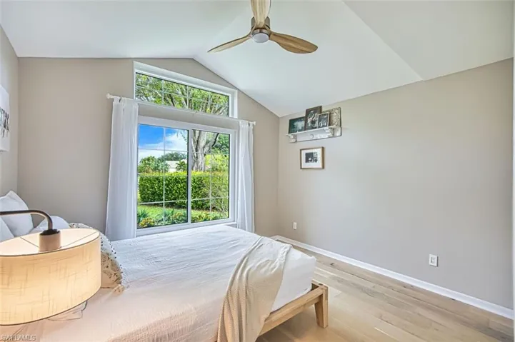 Bedroom with ceiling fan, light wood-style floors, and lofted ceiling