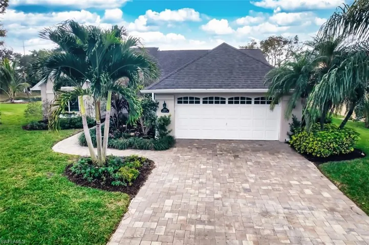 View of front of property featuring roof with shingles, a front lawn, decorative driveway, and stucco siding
