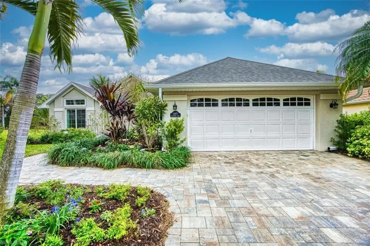 Ranch-style house with stucco siding, a shingled roof, and decorative driveway