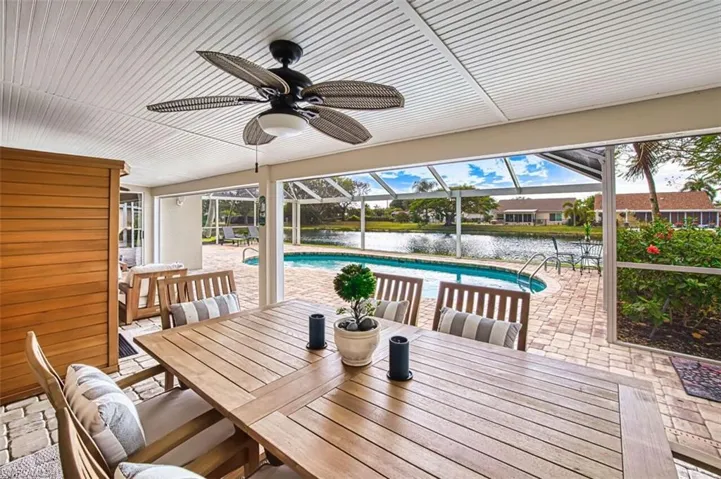 View of patio / terrace featuring an outdoor pool, a lanai, a sunroom, a water view, and outdoor dining space