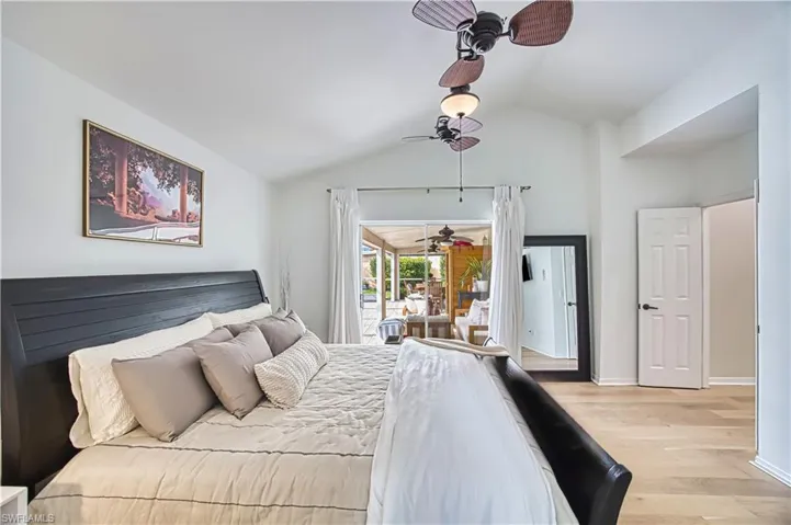 Bedroom featuring access to outside, light wood-style flooring, lofted ceiling, and ceiling fan