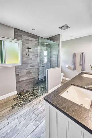 Full bathroom with double vanity, walk in shower, and wood tiled floors