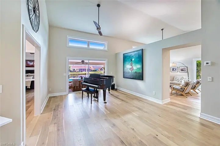 Sitting room featuring ceiling fan, light wood-type flooring, and a towering ceiling