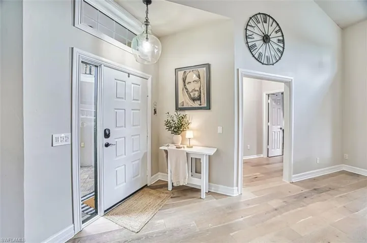 Entrance foyer with light wood-type flooring and high vaulted ceiling