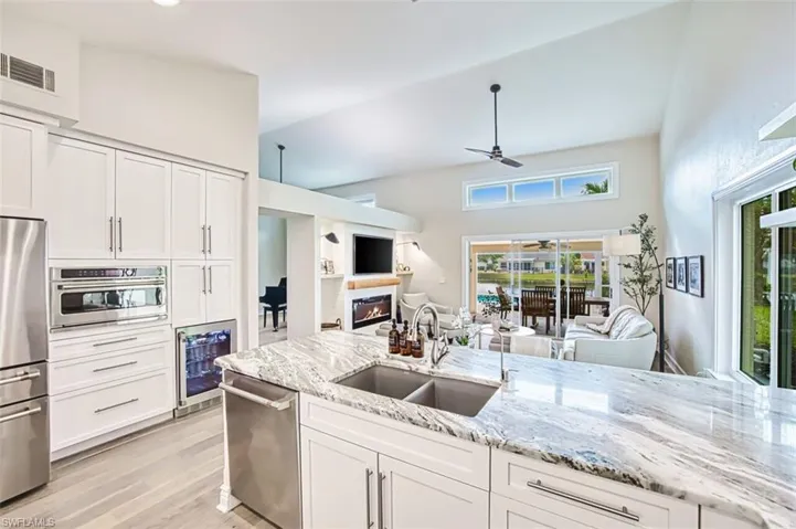 Kitchen featuring white cabinets, open floor plan, appliances with stainless steel finishes, light stone counters, and ceiling fan