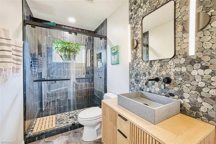 Full bathroom with vanity, a shower stall, and light stone finish floors