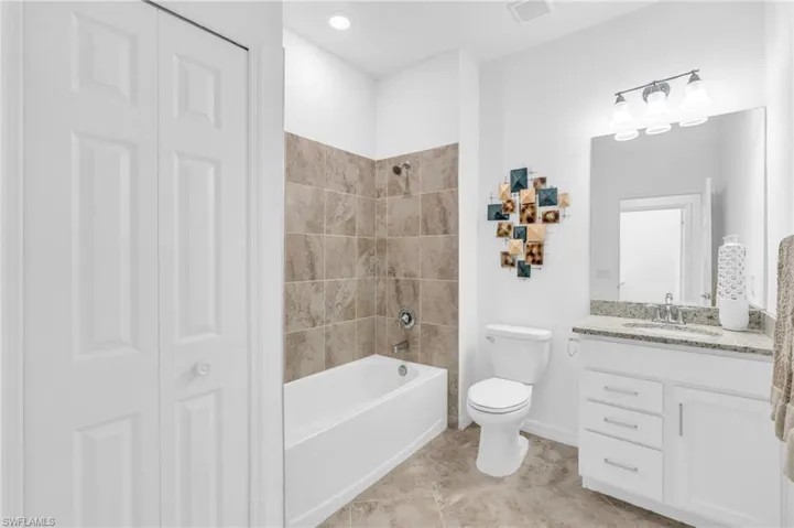 Full bathroom featuring toilet, vanity,  shower combination, and tile patterned flooring
