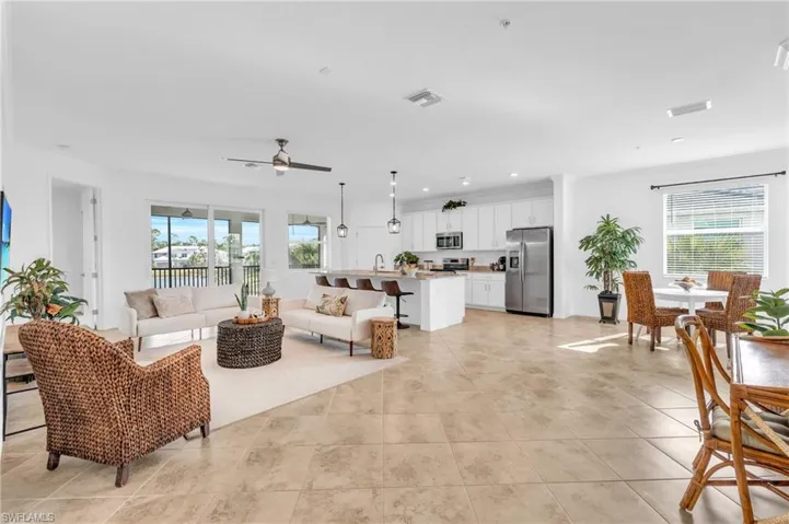 Living room featuring light tile patterned floors, ceiling fan, and a wealth of natural light