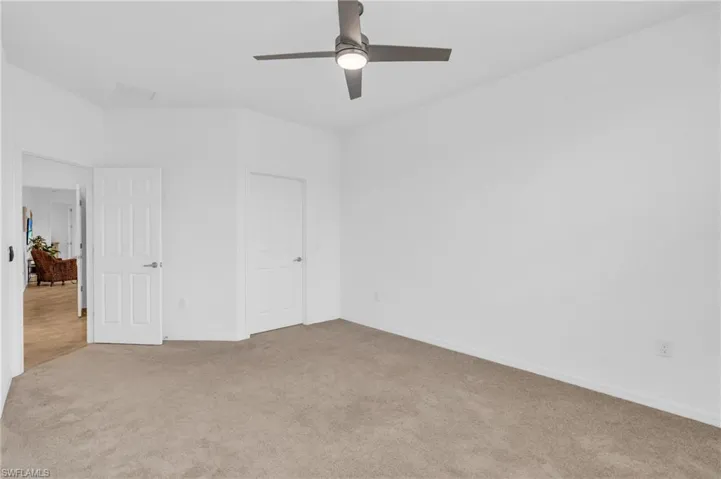 Unfurnished bedroom with ceiling fan and light carpet