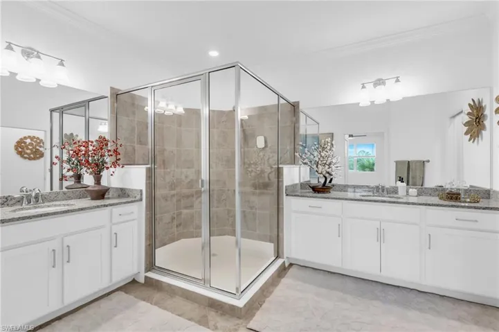 Bathroom featuring tile patterned flooring, crown molding, an enclosed shower, and vanity