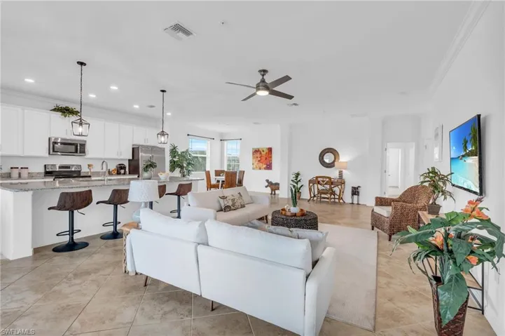 Living room with ceiling fan, light tile patterned floors, sink, and ornamental molding