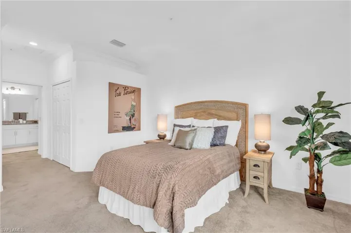 Bedroom featuring light colored carpet, crown molding, and ensuite bath