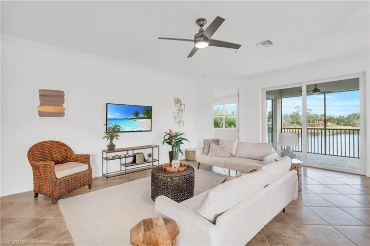 Tiled living room featuring ceiling fan and crown molding
