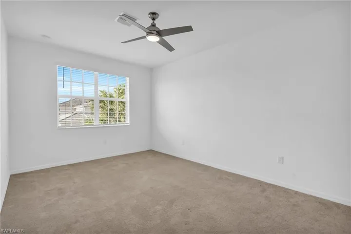 Unfurnished room with ceiling fan and light colored carpet
