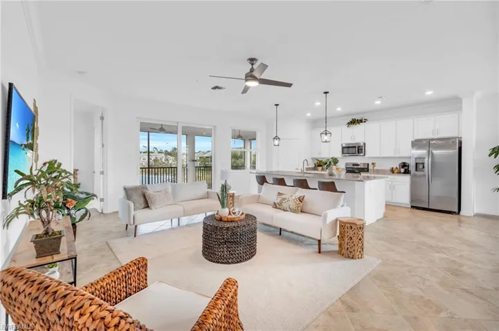 Tiled living room with ceiling fan, ornamental molding, and sink