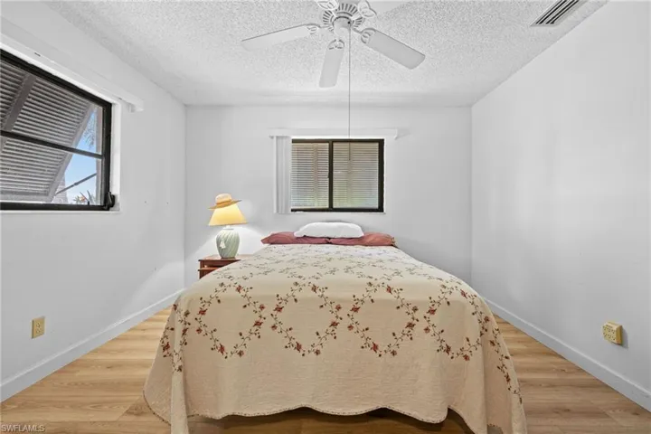 Wood-finish flooring, white walls, and a ceiling fan with integrated lighting