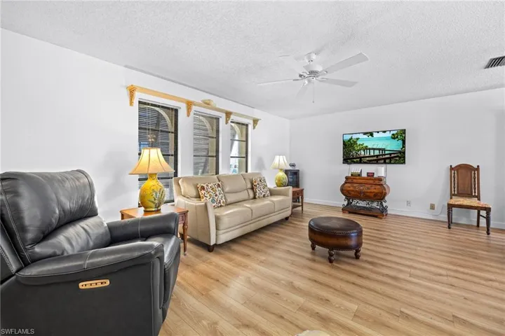 Wood-finish flooring, white walls, and a ceiling fan with integrated lighting