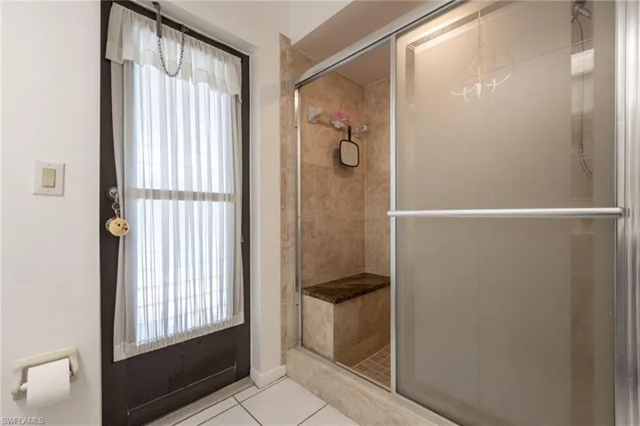 Tiled walk-in shower with a built-in bench, frosted glass sliding door, and decorative glass etching
