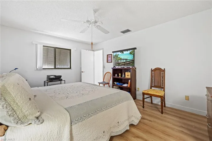 Wood-finish flooring, white ceiling fan, and window with horizontal blinds