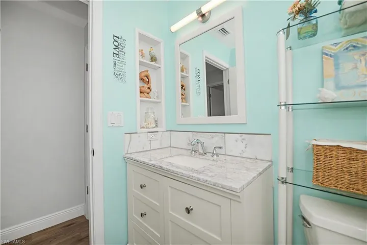 White vanity with a light-toned countertop, integrated sink, and chrome faucet