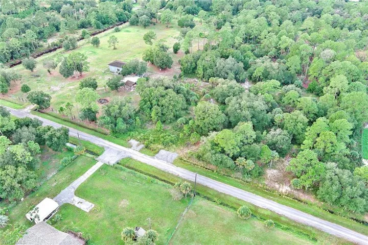 Aerial view of property and surrounding area featuring a forest and rural landscape
