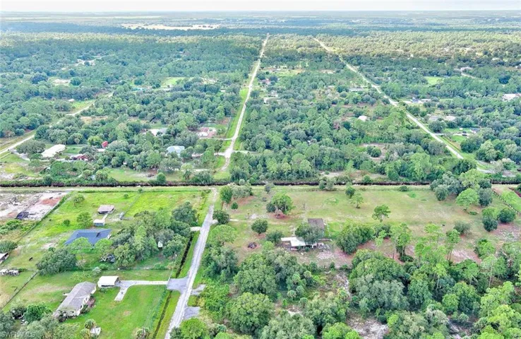 Aerial view of property and surrounding area with a forest