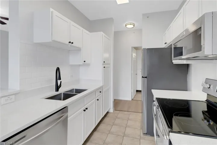 Kitchen with white cabinetry, appliances with stainless steel finishes, and sink