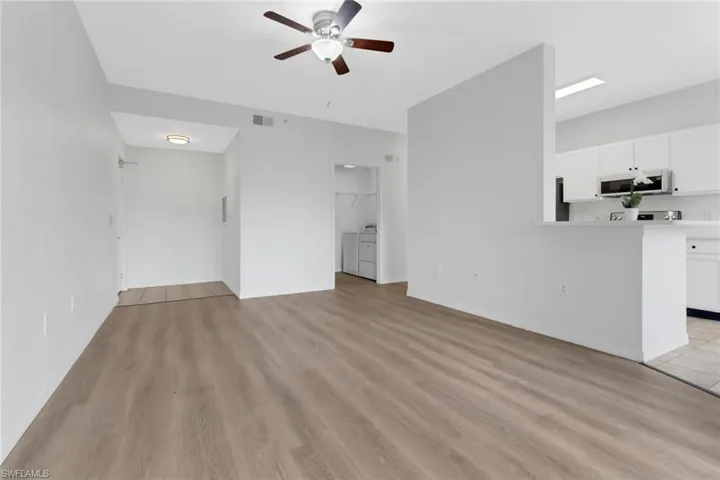Unfurnished living room with ceiling fan, light hardwood / wood-style floors, and washer and dryer