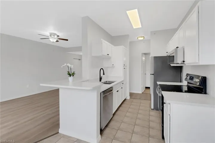 Kitchen featuring stainless steel appliances, light hardwood / wood-style floors, white cabinetry, sink, and kitchen peninsula
