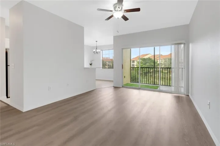 Unfurnished living room featuring hardwood / wood-style flooring and ceiling fan with notable chandelier
