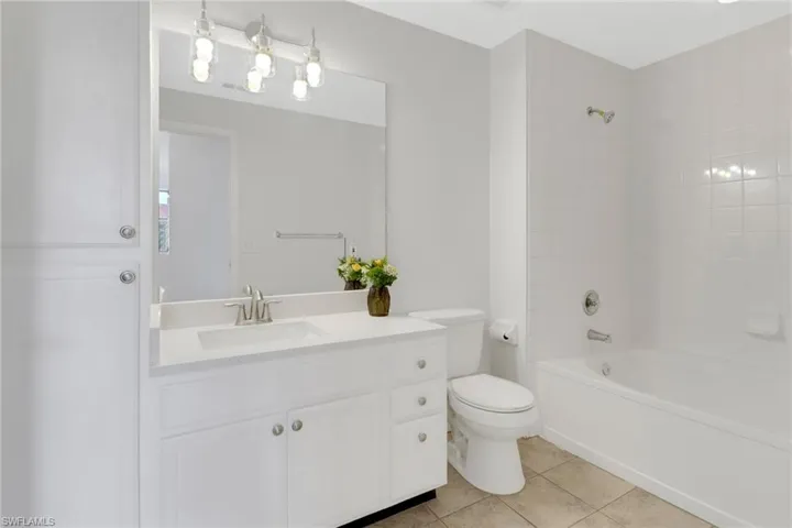 Full bathroom featuring vanity, tile patterned floors, toilet, and tiled shower / bath combo