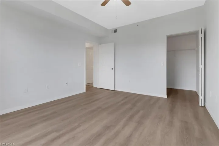 Unfurnished bedroom with light hardwood / wood-style floors, ceiling fan, a walk in closet, and a closet