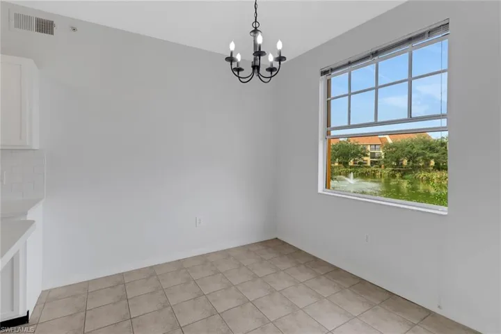 Unfurnished dining area with light tile patterned flooring, a water view, an inviting chandelier, and a healthy amount of sunlight
