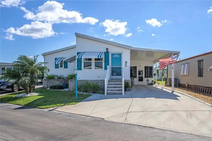 Manufactured / mobile home featuring a front lawn and a carport