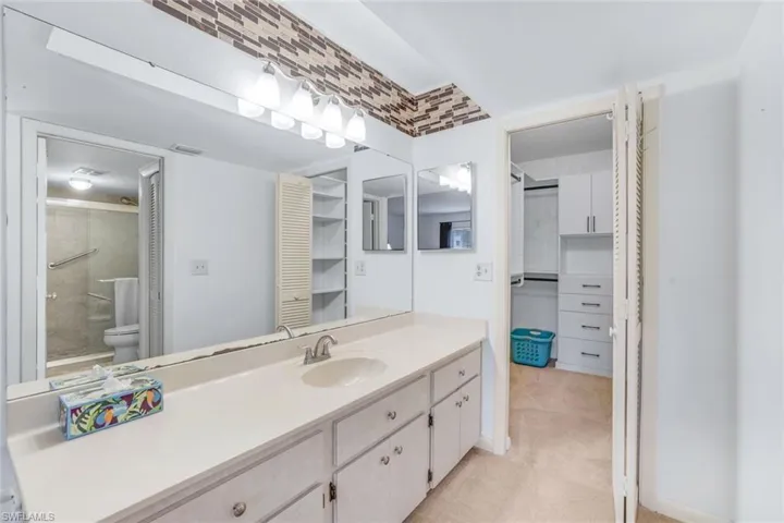 Bathroom with vanity, toilet, walk in shower, and tile patterned floors