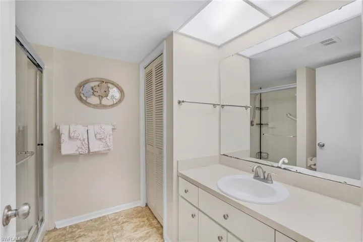 Bathroom with a shower with shower door, tile patterned flooring, and vanity