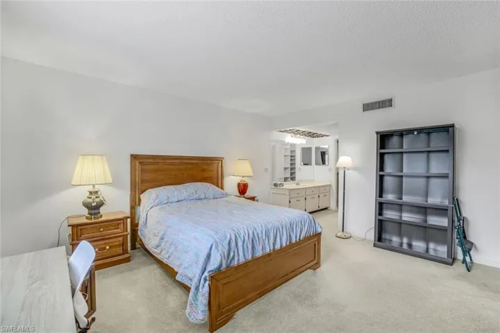 Carpeted bedroom with a textured ceiling and ensuite bath