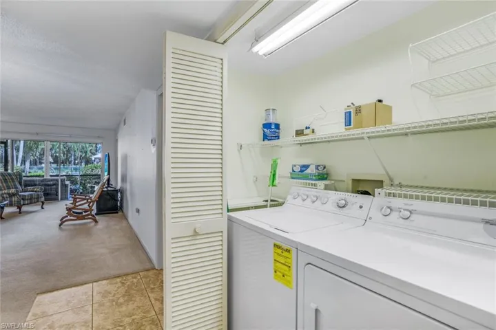 Clothes washing area featuring washing machine and dryer and light colored carpet