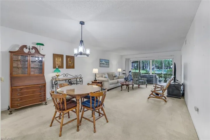 Dining space with a textured ceiling, an inviting chandelier, and light colored carpet
