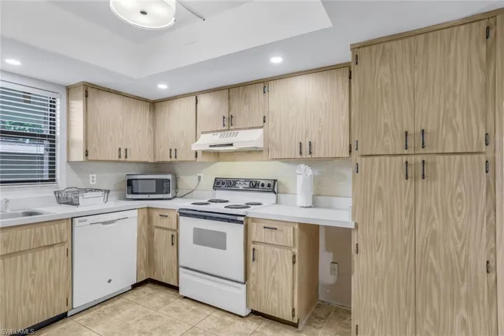 Kitchen featuring backsplash, white appliances, and light tile patterned flooring
