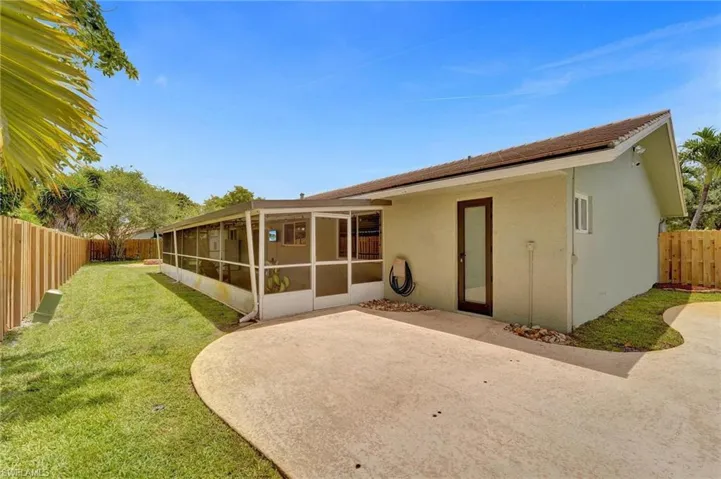 Rear view of property featuring a sunroom, a patio area, and stucco siding