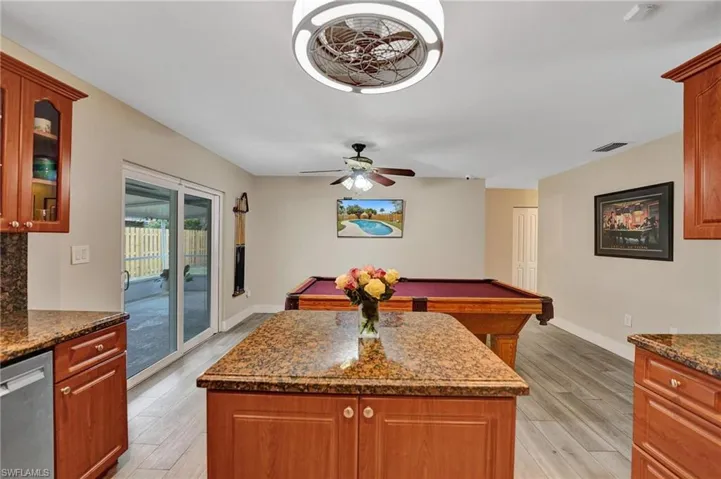 Kitchen featuring stainless steel dishwasher, light wood-style flooring, a kitchen island, and billiards table