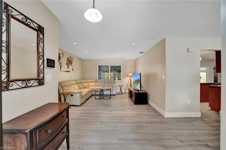 Living room with light wood-type flooring, healthy amount of natural light, baseboards, and recessed lighting