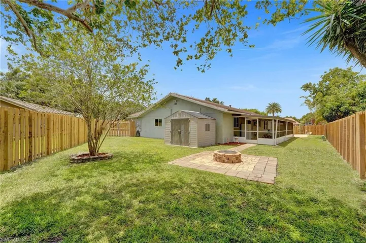View of yard with a sunroom, an outdoor fire pit, and a patio area