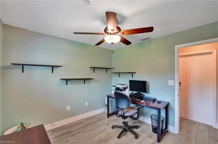 Office area featuring a ceiling fan, light wood finished floors, and baseboards