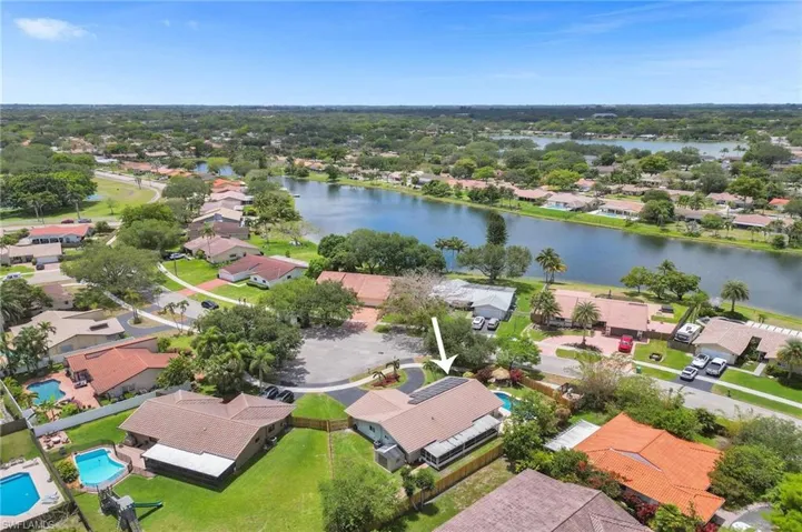 Aerial perspective of suburban area featuring a nearby body of water and a pool area