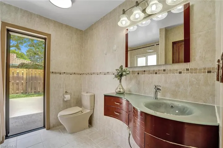 Bathroom featuring tile walls, tile patterned floors, vanity, and toilet